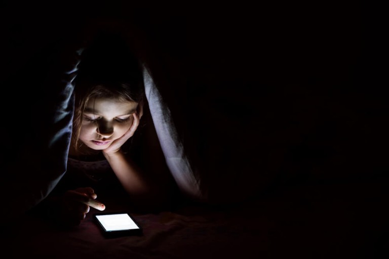למה ילדי קשב וריכוז שונאים ללכת לישון? ילד עם טלפון מתחת לשמיכה